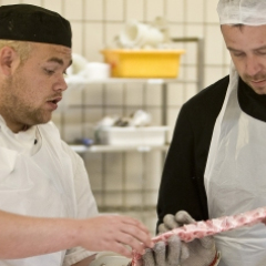 Slagtersvend instruerer en detailslagterlærling