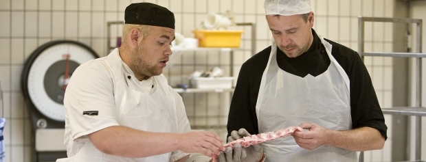 Slagtersvend instruerer en detailslagterlærling