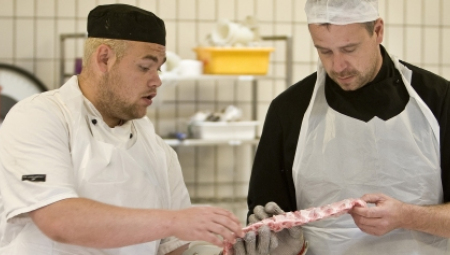 Slagtersvend instruerer en detailslagterlærling